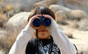 Child with binoculars looking directly at the camera