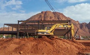 Picture of a backhoe shoveling red dirt